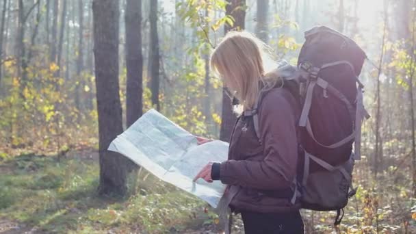 Een vrouwelijke reiziger is op zoek naar een weg, kijken naar een kaart van de omgeving. - Video
