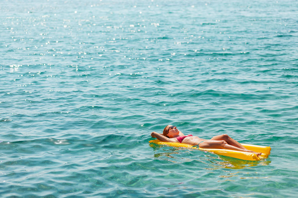 junge Frau schwimmt auf der Matratze im Meer - Foto, Bild