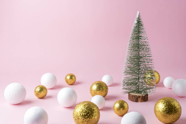 Gold and white glitter ball decoration with small Christmas tree on pink background. New Year minimal concept. - Фото, изображение