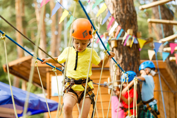 Kleines Mädchen klettert auf Seilen im Extrempark  - Foto, Bild