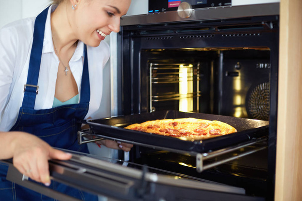 Happy young woman cooking pizza at home - Foto, Imagen