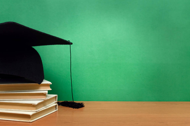 Stack of books and graduation cap on green school board background. Back to school. - Foto, Imagen