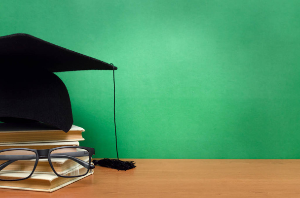 Stack of books, glasses and graduation cap on green school board background. Back to school. - Foto, Imagem