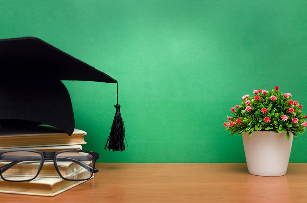 Stack of books, glasses and graduation cap on green school board background. Back to school. - Фото, зображення