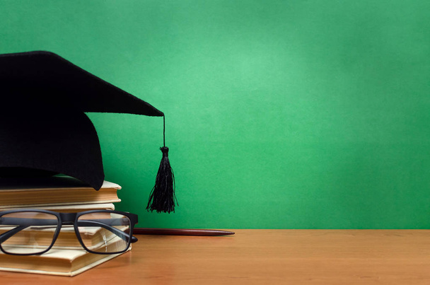 Stack of books, glasses and graduation cap on green school board background. Back to school. - Foto, immagini
