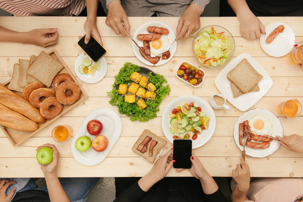 Grupa ludzi jedzących razem kolację przy drewnianym stole - Zdjęcie, obraz