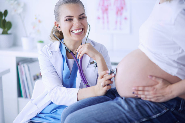 Усміхнена жінка-лікар показує фотографії на планшеті вагітній молодій жінці в лікарні
. - Фото, зображення