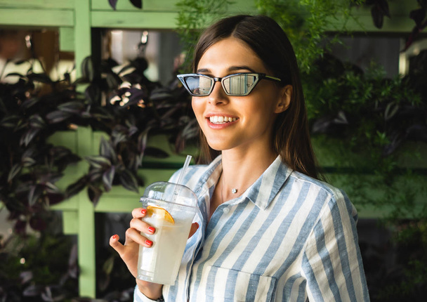 Красива молода жінка з пластиковою чашкою свіжого коктейлю
 - Фото, зображення