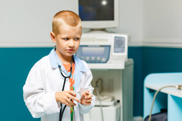 Мальчик в медицинской форме играет со стетоскопом
 - Фото, изображение