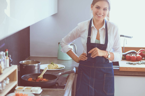 Портрет молодой женщины, стоящей со скрещенными руками на фоне кухни - Фото, изображение