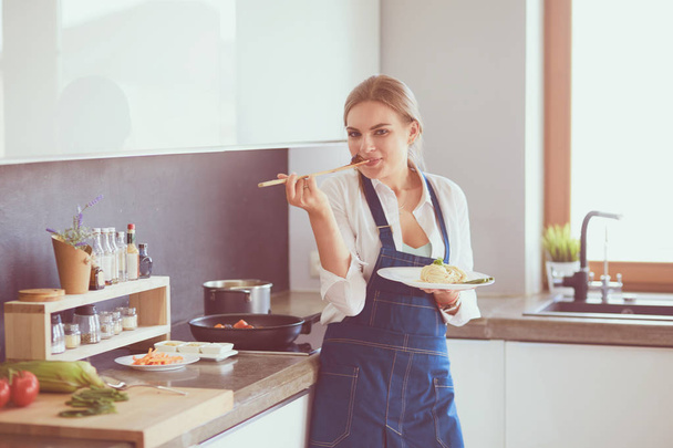 Young woman standing by the stove in the kitchen - Photo, Image
