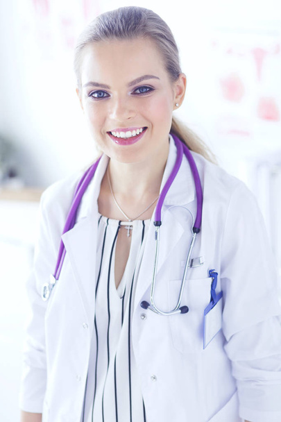 Smiling female doctor with a medical stethoscope in uniform standing - Foto, afbeelding