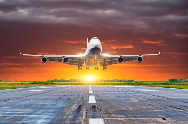 Avião de passageiros a aterrar ao pôr-do-sol numa pista
 - Foto, Imagem