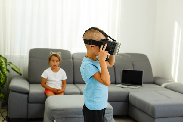 Hermano y hermana usando auriculares de realidad virtual en la sala de estar
 - Foto, Imagen