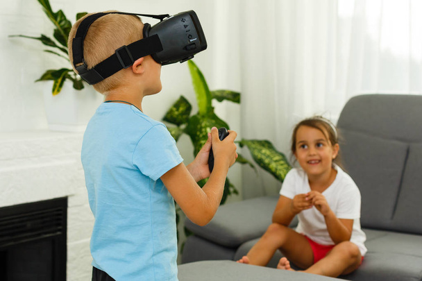 Brother and sister using virtual reality headsets in living room - Photo, Image