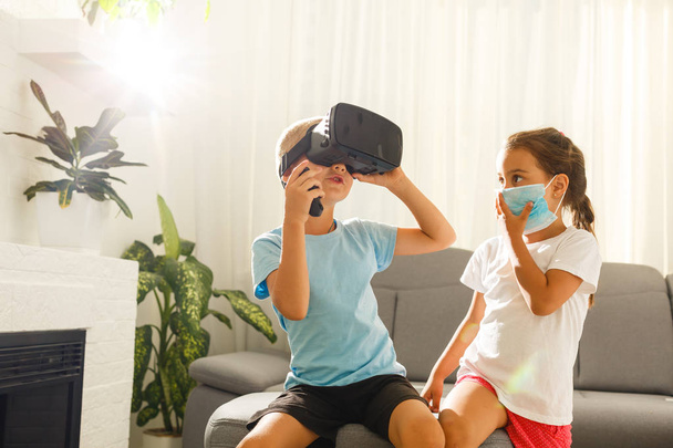 Hermano y hermana usando auriculares de realidad virtual en la sala de estar
 - Foto, imagen
