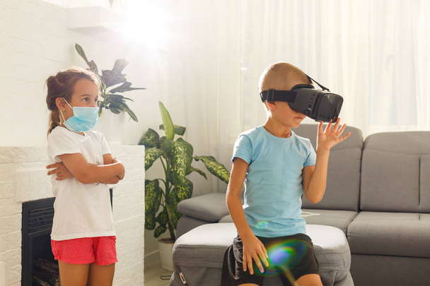 Broer en zus met behulp van virtuele realiteit headsets in woonkamer - Foto, afbeelding