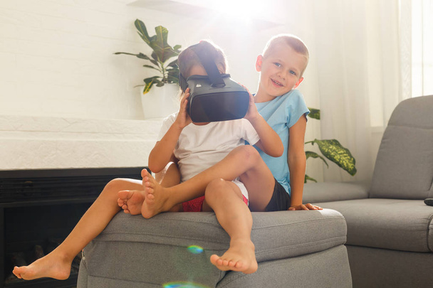 Брат и сестра используют гарнитуры виртуальной реальности в гостиной
 - Фото, изображение