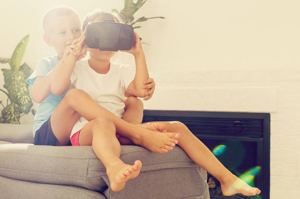 Frère et sœur utilisant des casques de réalité virtuelle dans le salon
 - Photo, image
