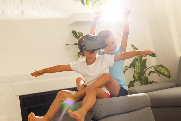 Fratello e sorella utilizzando cuffie realtà virtuale in soggiorno
 - Foto, immagini