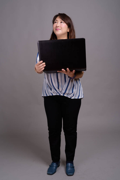 Full length portrait of Japanese businesswoman using laptop computer - Zdjęcie, obraz