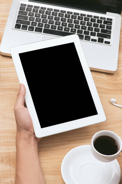 human hands holding black tablet pc with blank screen and coffee cup on wooden table - Photo, Image