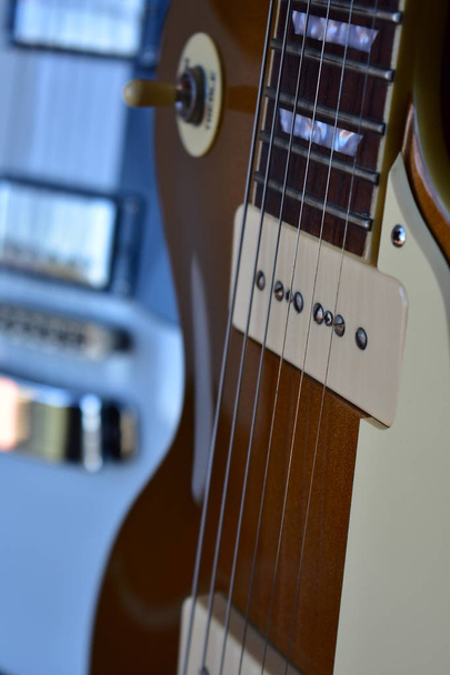 Detalhes de guitarras elétricas douradas e brancas. Body, P90 captadores, ponte, pescoço, pickguard, fretboard e cordas
.  - Foto, Imagem