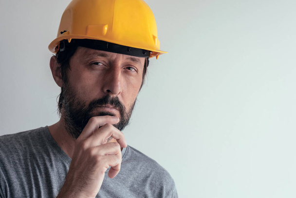 Portrait of serious thoughtful construction engineer isolated on bright background - Photo, Image
