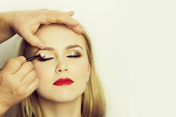 Girl with closed eyes and red lips getting makeup - Foto, Imagen