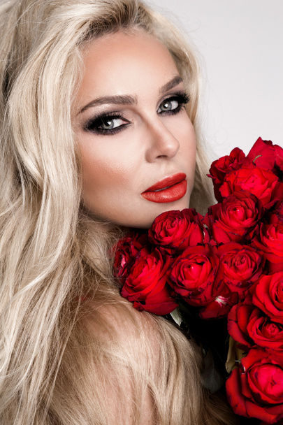 Portréja egy gyönyörű szőke női modell, hosszú, gyönyörű haj. Modell, szexi fehérnemű, gazdaság vörös rózsa. - Fotó, kép