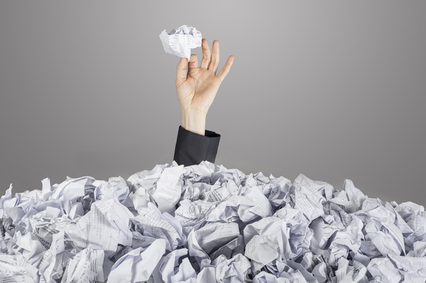 Person under pile of documents with hand holding a crumpled paper - Fotoğraf, Görsel