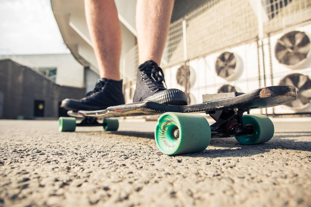 close-up of legs and longboard standing on asphalt - Foto, Imagem