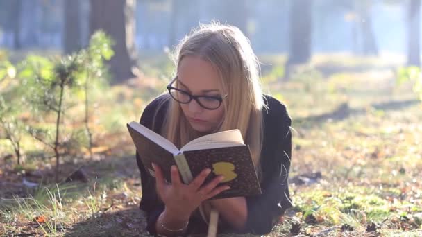 girl with glasses reading a book - Materiał filmowy, wideo