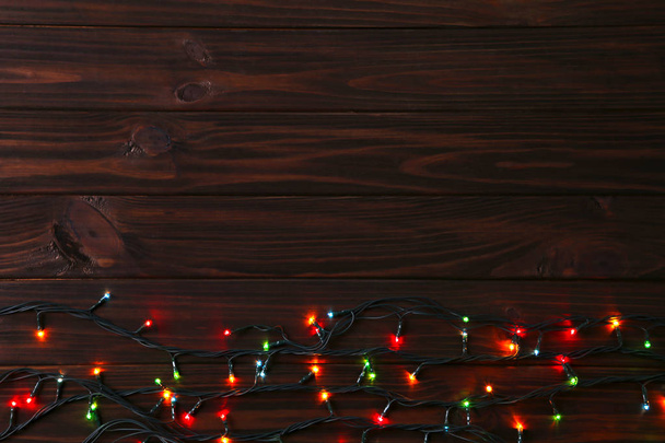 Різдвяна гірлянда світиться на коричневому фоні, копіює простір. Новорічна композиція
 - Фото, зображення