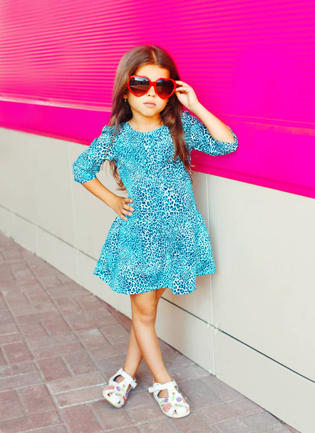 Pembe renkli arka plan üzerinde leopar baskı elbiseli güzel küçük kız - Fotoğraf, Görsel
