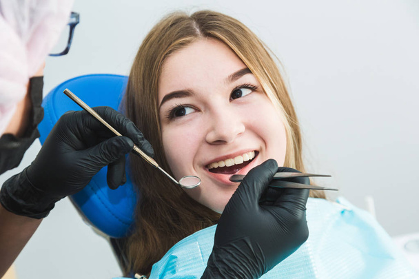 Dental clinic. Reception, examination of the patient. Teeth care. Young girl undergoes a dental examination by a dentist - Φωτογραφία, εικόνα