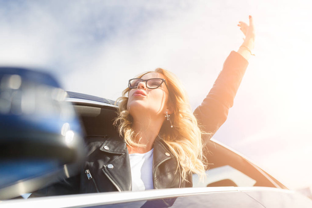 Photo of young woman with glasses popping out of black car - Foto, Imagem