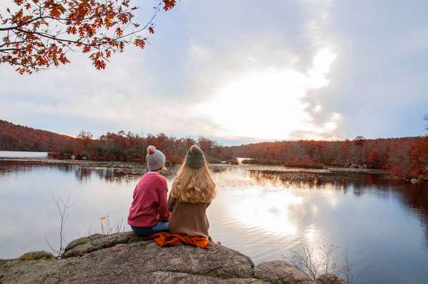 Two girls traveler in autumn clothes looking at amazing lake and forest, wanderlust travel concept - Valokuva, kuva