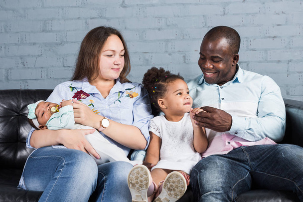 Happy multiethnic family sitting on the sofa in modern interior - Photo, Image