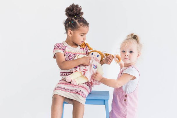 Дві маленькі дівчата грають на білому тлі
 - Фото, зображення