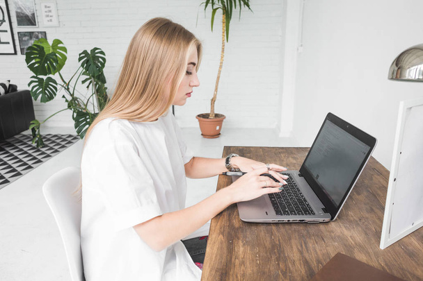 Young business woman working at home behind a laptop. Creative Scandinavian style workspace - Fotografie, Obrázek