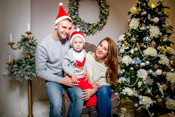 Happy family, father, mother and son, in the morning in living room decorated for Christmas. They open presents and have fun. New Year's and Christmas theme. Holiday mood. - Photo, image