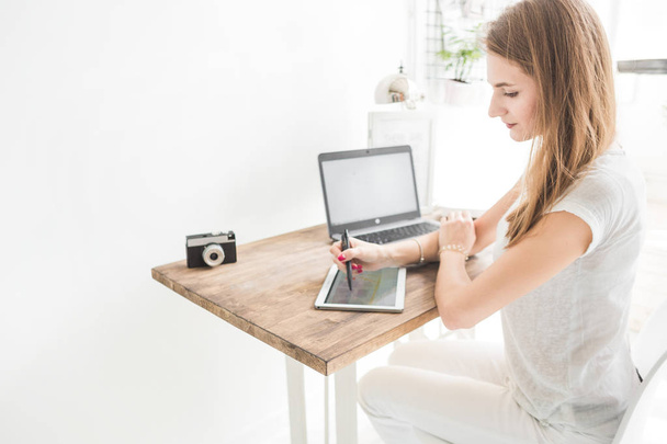 Young business woman working at home and draws on the tablet. Creative Scandinavian style workspace - Φωτογραφία, εικόνα