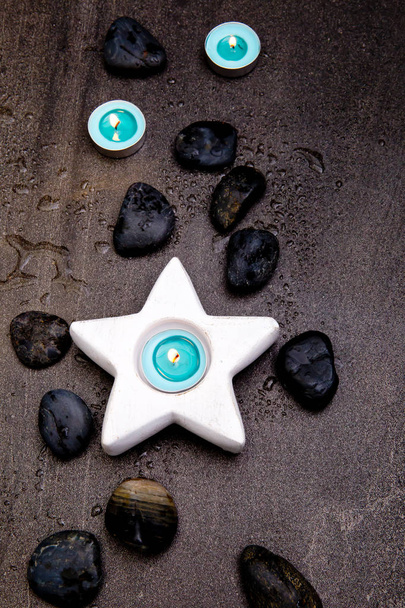 Velas azuis turquesa em suporte de vela estrela branca em fundo de ardósia cinza com gotas de água
 - Foto, Imagem