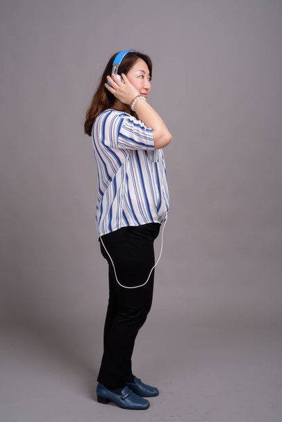 Portrait of mature Japanese businesswoman with headphones - Foto, Bild