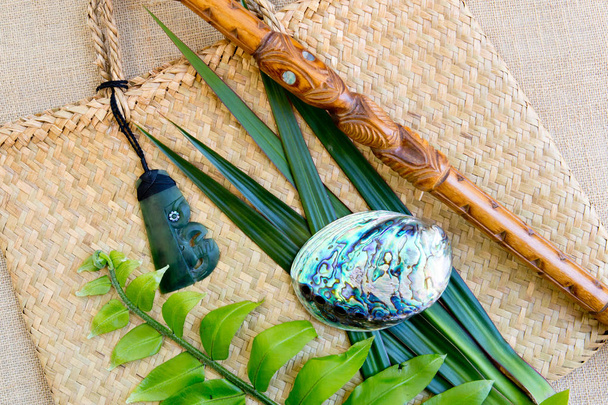 Nowa Zelandia - Maori obiekty tematyczne - naszyjnik Jade Hotel Pounamu Tiki Toki, Paua powłoki i drewniane Tokotoko rozmawia kij z paproci i lnu liści na tle lniane torby tkane latawiec - Zdjęcie, obraz
