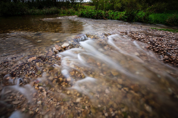 long exposure of rocky mountain river in summer with high water stream level in forest  - Photo, Image
