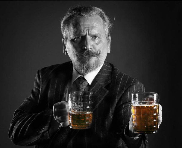 closeup portrait of an adult male with a mustache and beard, wearing glasses and a business suit with beer mug - Fotografie, Obrázek