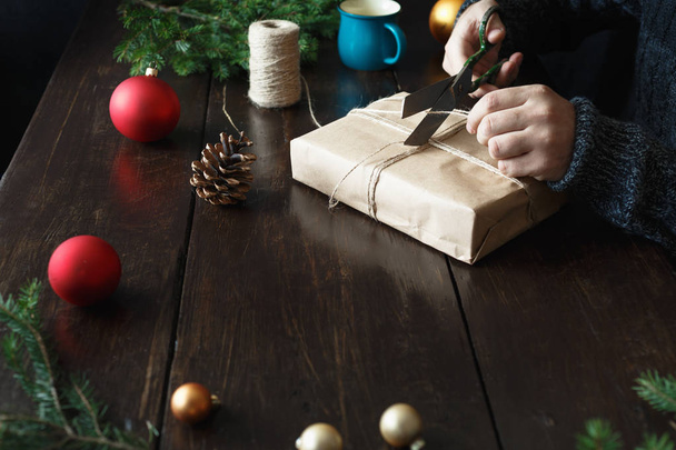 Male hands preparing Christmas present on wooden table. Rustic Christmas background - Fotó, kép