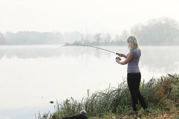 Girl fishing foggy autumn morning on the river - Foto, imagen